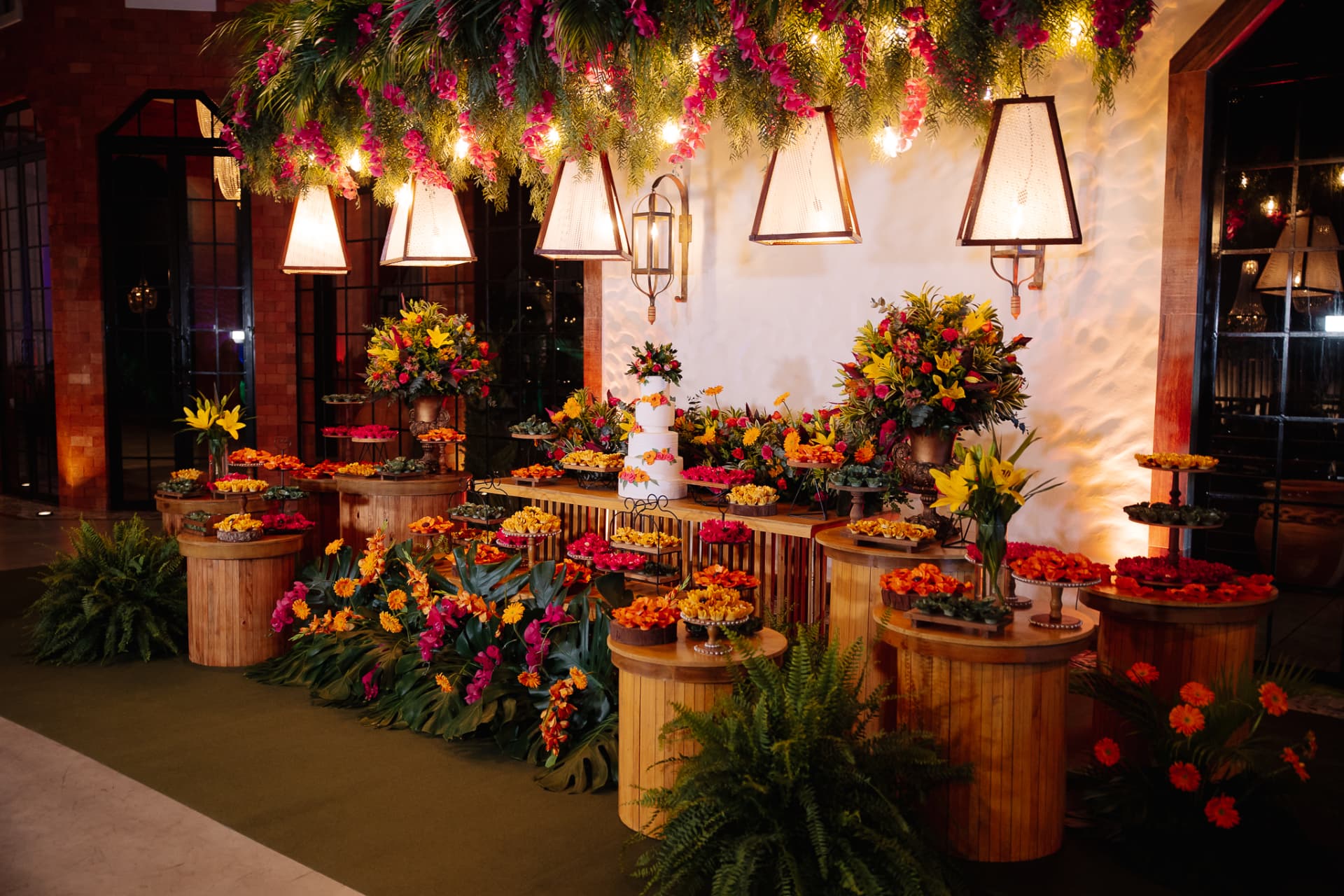 Mesa de bolo e doces com decoração floral suspensa
